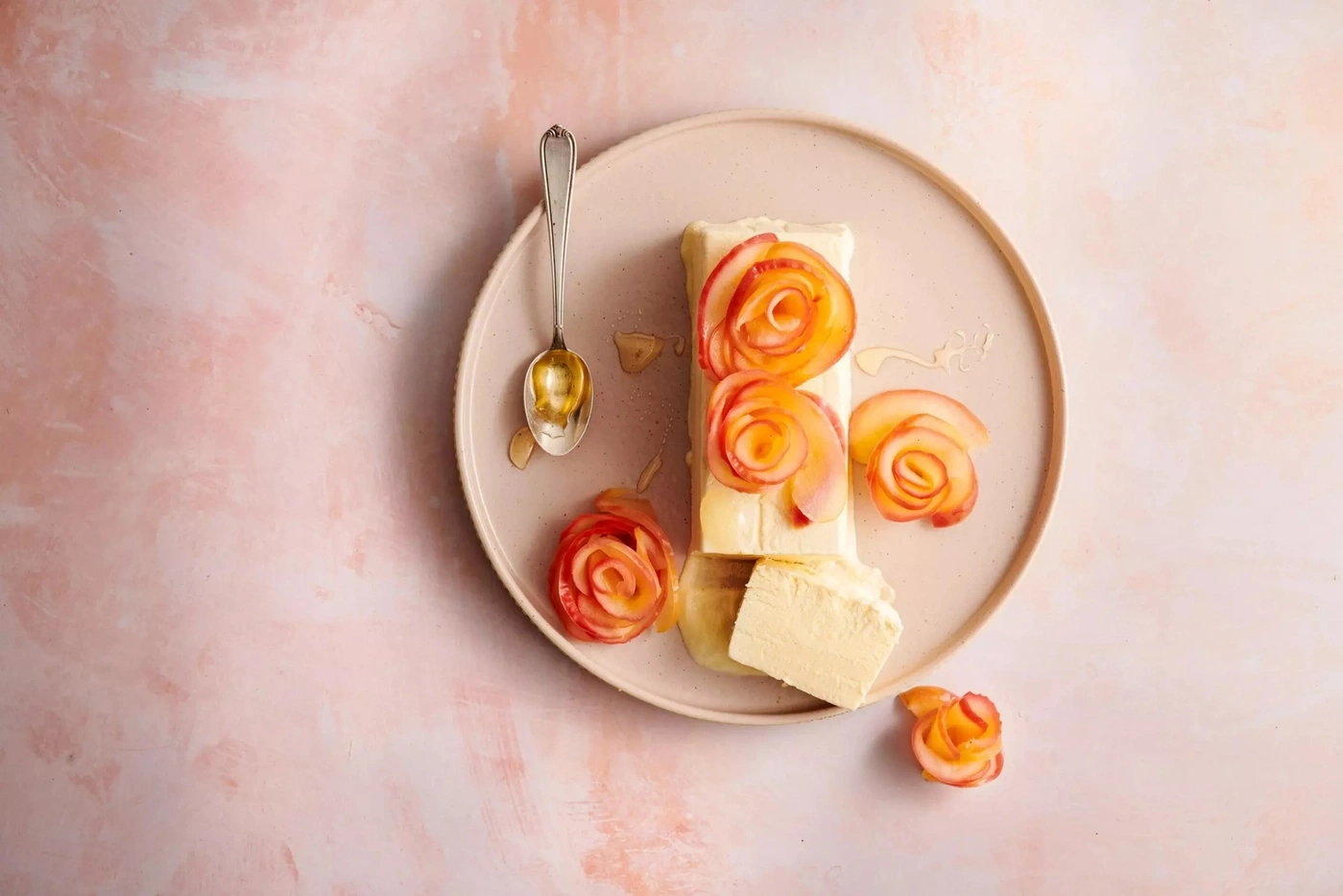 Ein süßes Dessert mit gefrorenem Joghurt und Apfelrosen auf einem Teller.