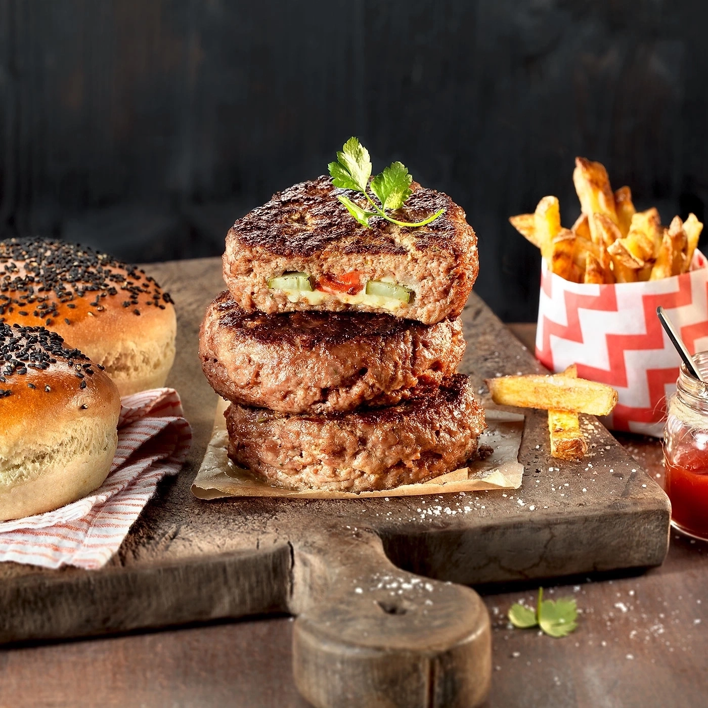 Burger-Turm mit Pommes und Brötchen auf Holzbrett, lecker