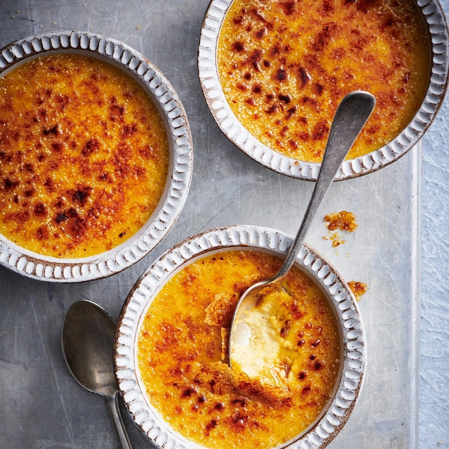 Drei Schalen Crème brûlée mit Löffeln auf einem Tablett