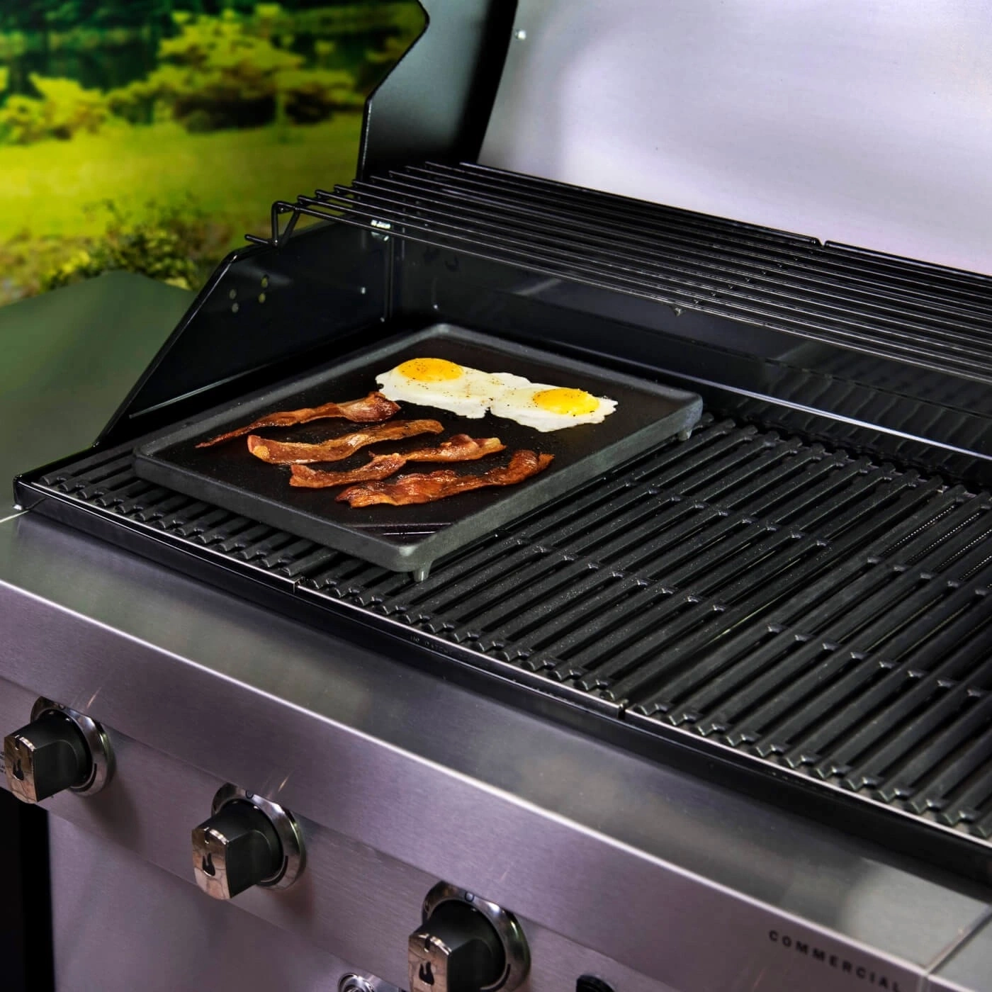 Grill mit Speck und Eiern, die auf einer Grillplatte zubereitet werden.