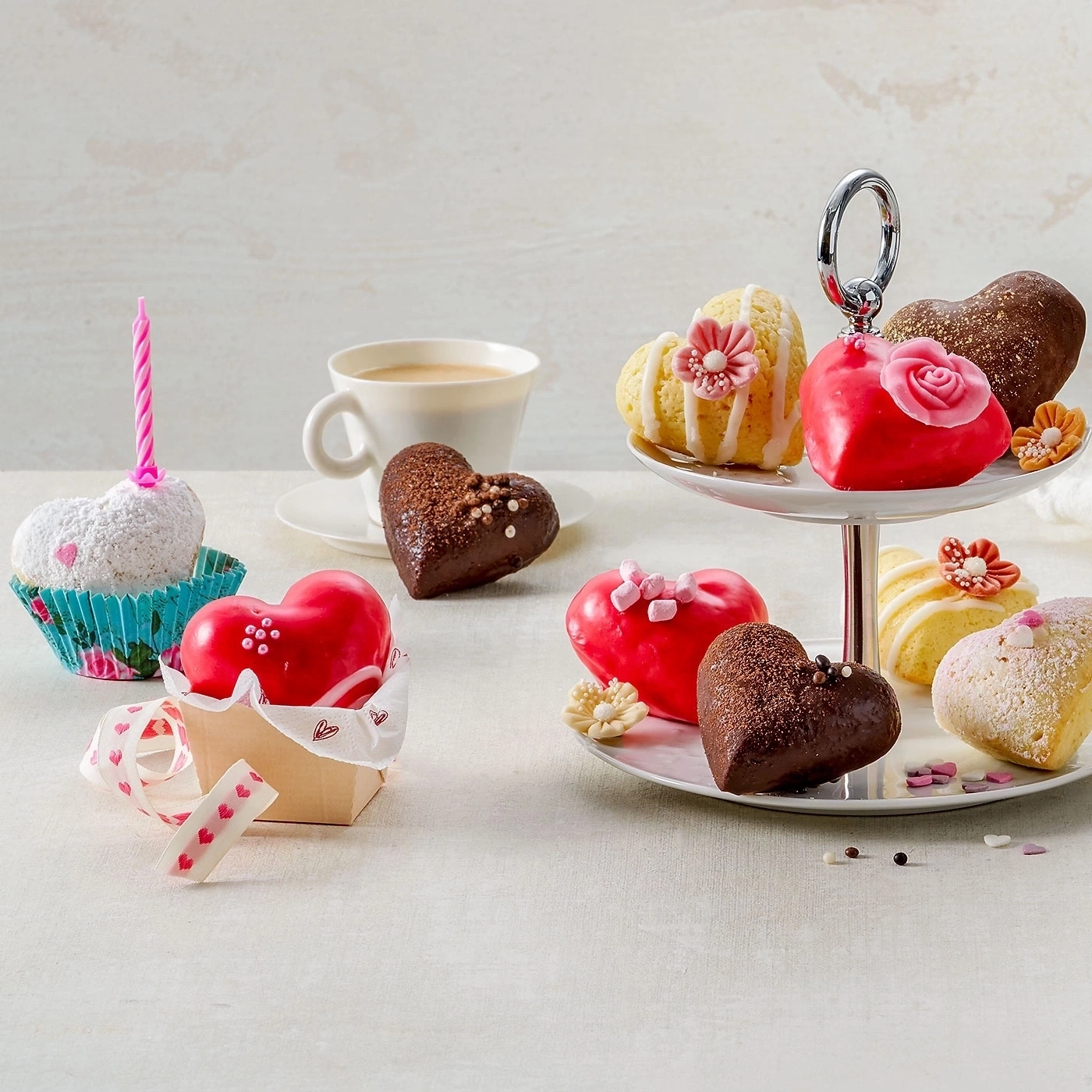 Herzförmige Kuchen, Cupcakes, Kaffee und eine Kuchenständer.