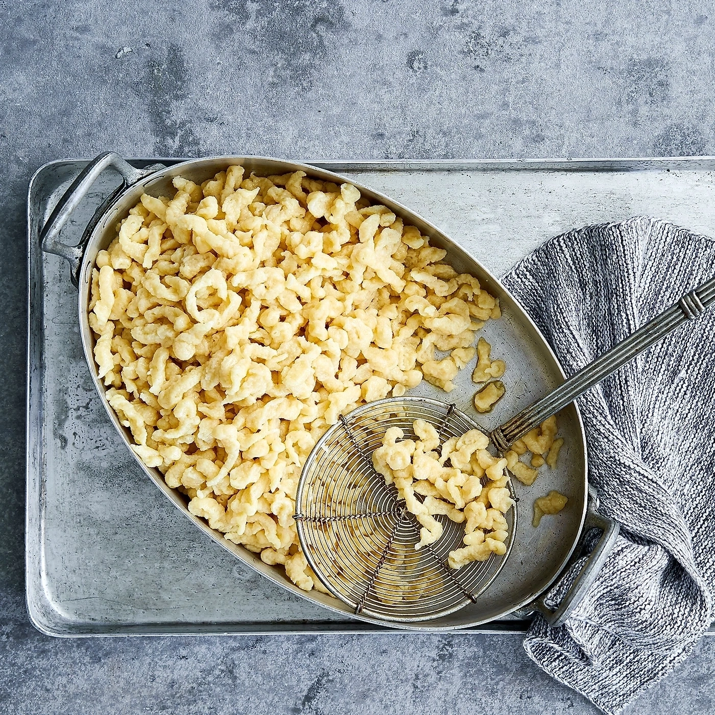 Gekochte Spätzle in einer ovalen Schüssel auf einem Metalltablett