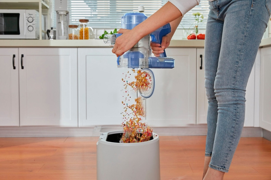 TINECO Akku-Hand-und Stielstaubsauger Pure One S11 LED Display beutellos B-WARE Person entleert Staubsauger in einen Behälter in der Küche. Reinigung.