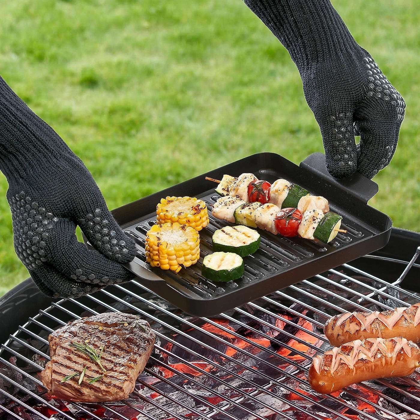 Grillen mit Gemüse, Fleisch und Würstchen. Hände mit Handschuhen.