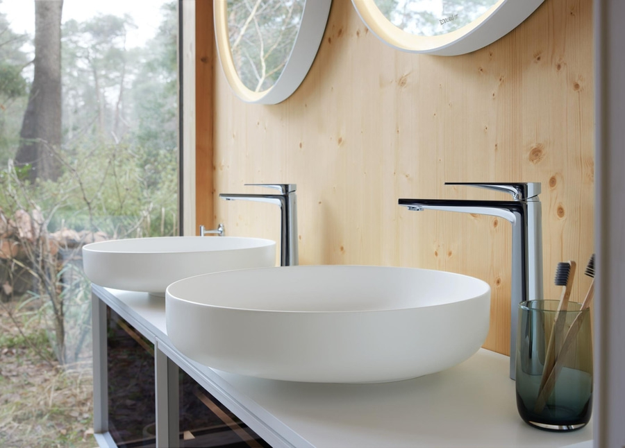 Zwei Waschbecken mit Wasserhähnen und Spiegeln in einem Badezimmer mit Holzverkleidung