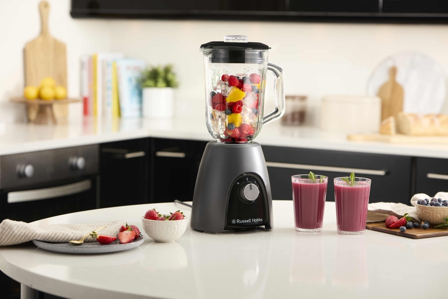 Küchenszene mit Mixer, Smoothie-Gläsern und Früchten auf einem Tisch
