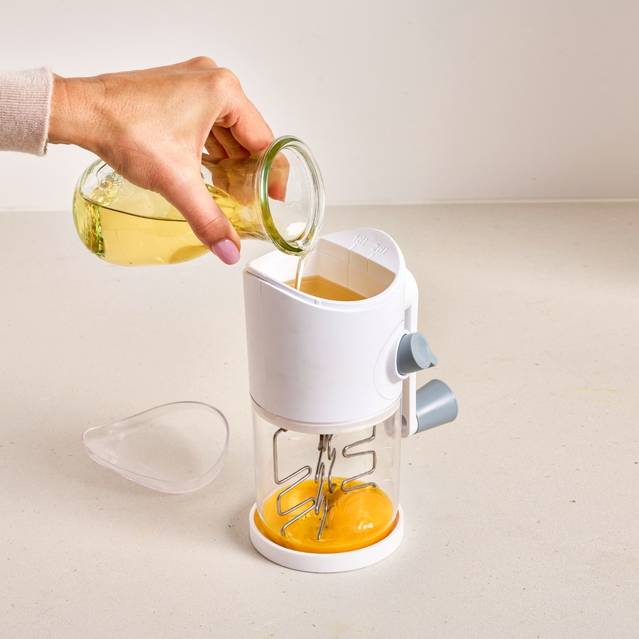 Person gießt Öl in ein Küchengerät mit Eiern. Küche, Kochen, Öl.