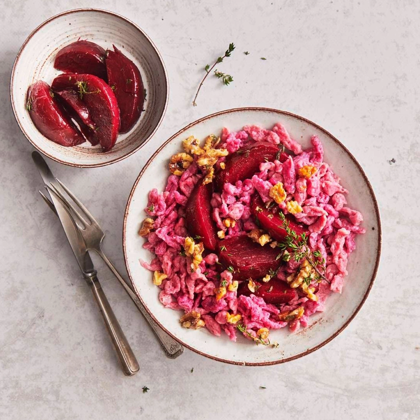 Rote-Bete-Spätzle mit Walnüssen und Thymian, serviert auf einem Teller.