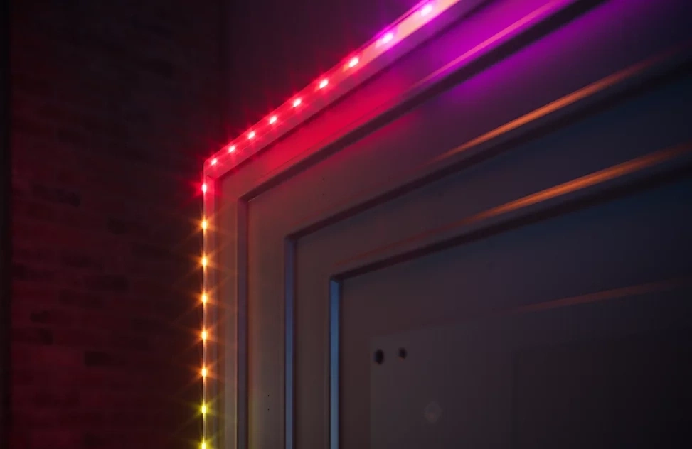 LED-Lichterkette beleuchtet eine Tür und eine Ziegelwand mit roten und violetten Farben.