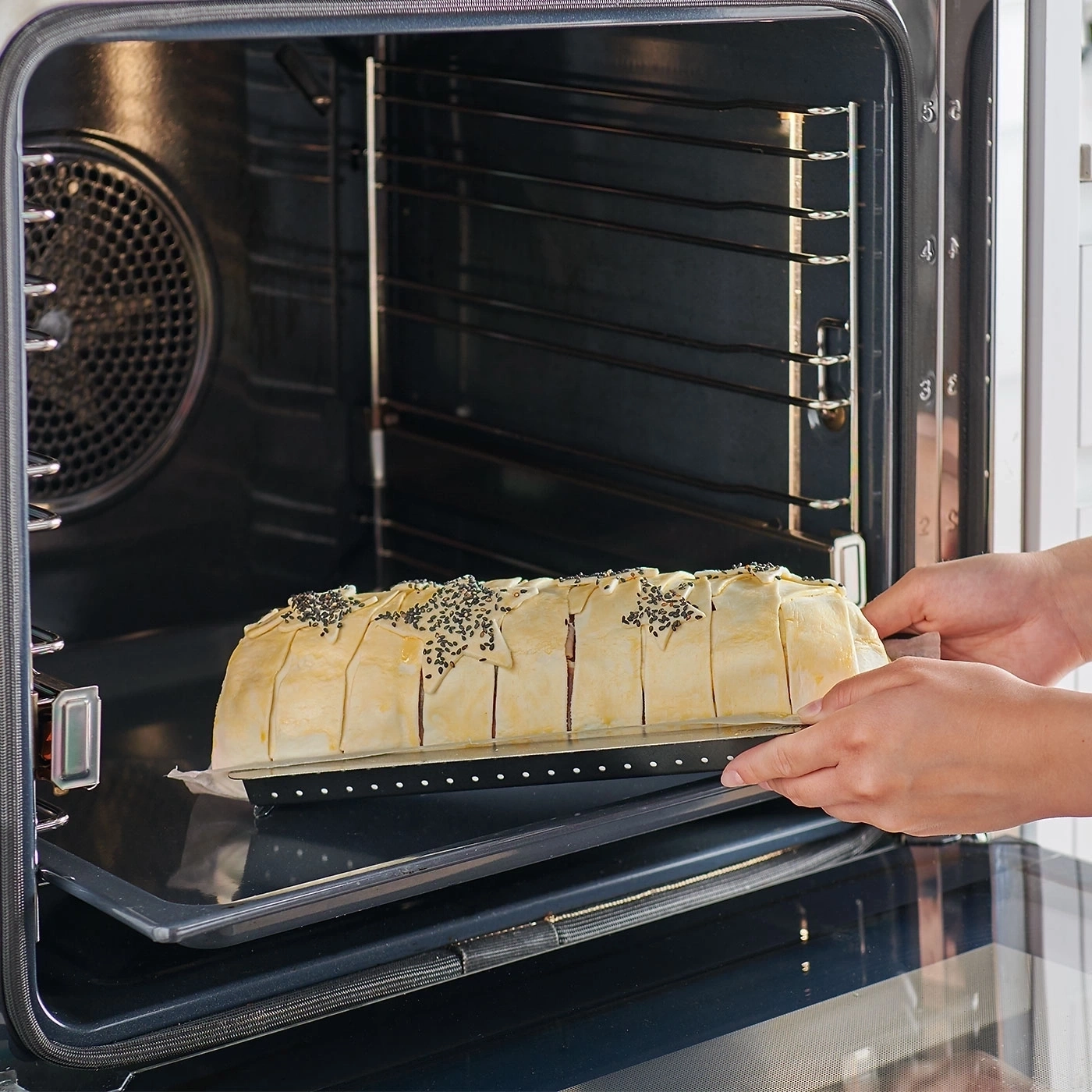 Ein Backofen mit einem Gericht, das gerade hineingelegt wird, Nahaufnahme