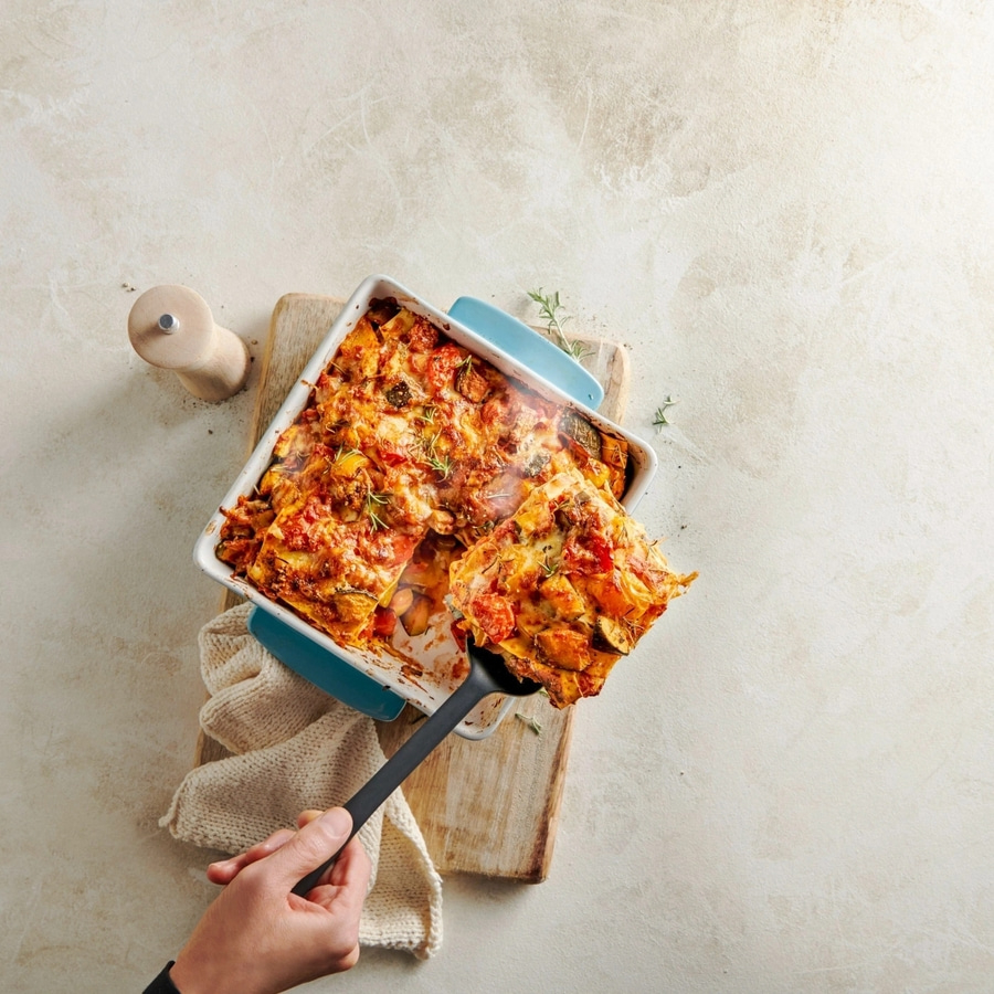 Lasagne wird aus der Auflaufform gehoben, auf einem Holzbrett serviert, lecker.