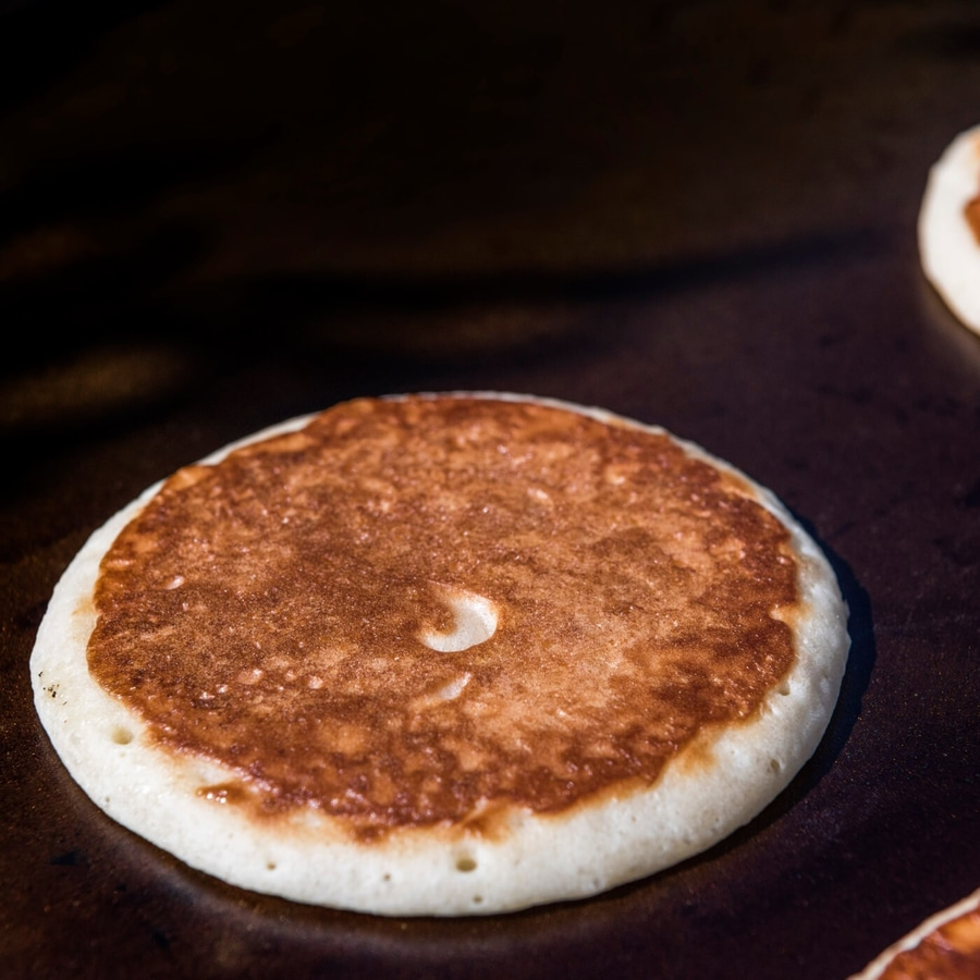 Nahaufnahme eines Pfannkuchens, der auf einer Kochplatte gebraten wird, mit brauner Oberfläche