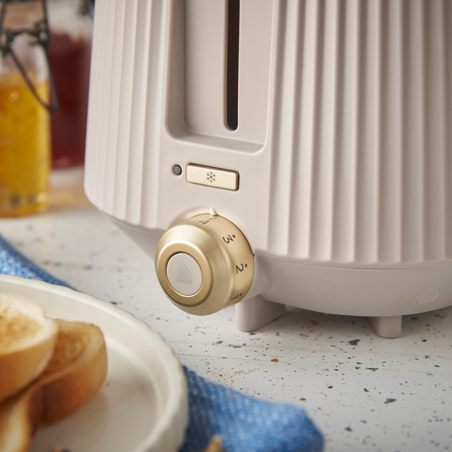 Toaster mit goldfarbenen Knöpfen und Toastscheiben auf einem Teller