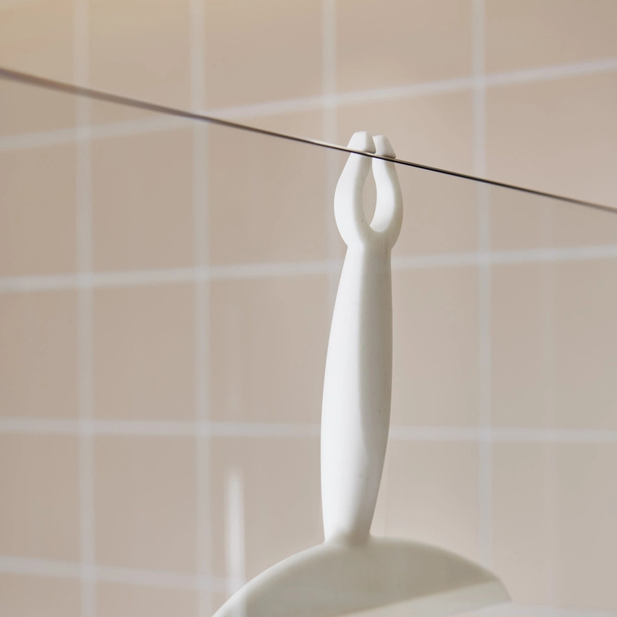Weißer Besen hängt an einer Schnur vor einer gefliesten Wand