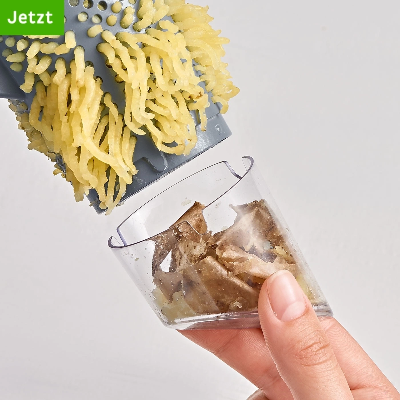 Kartoffelreibe mit Kartoffeln und Behälter, gehalten von einer Hand