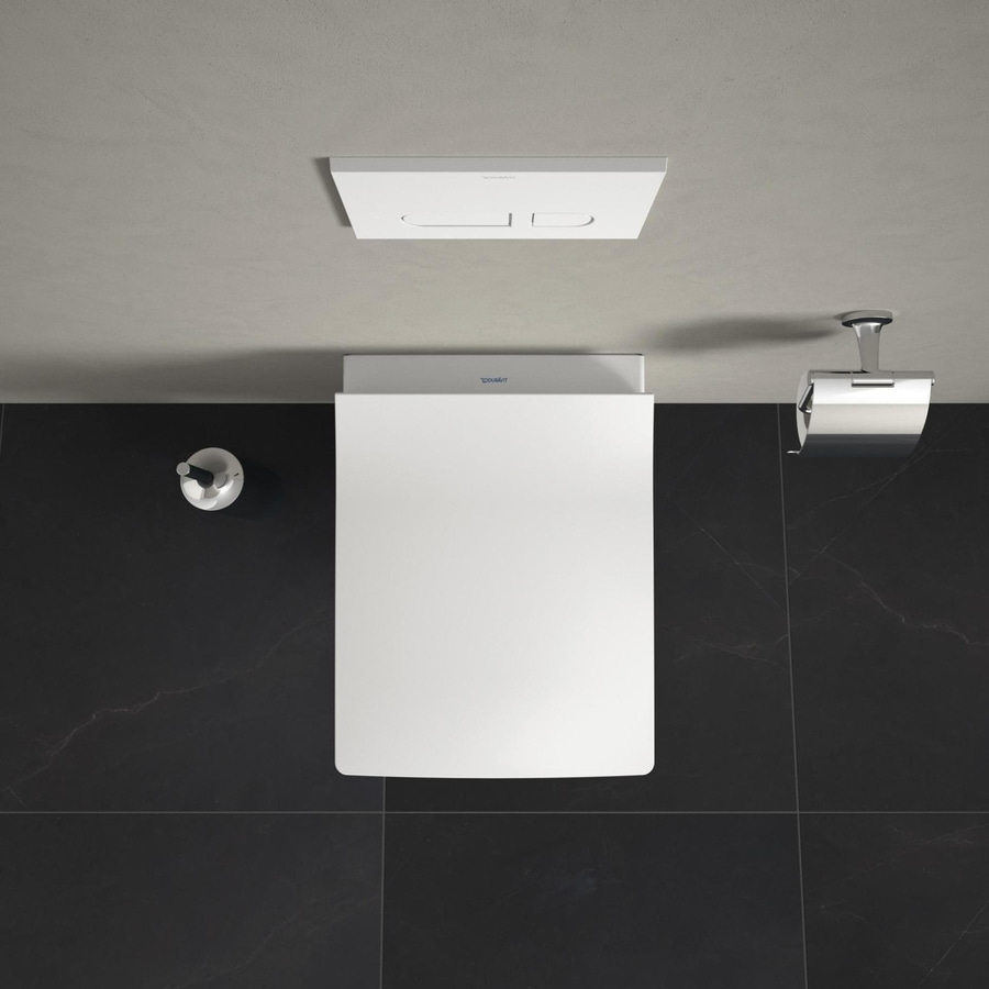 Draufsicht auf eine weiße Toilette mit schwarzem Fliesenboden und Zubehör.