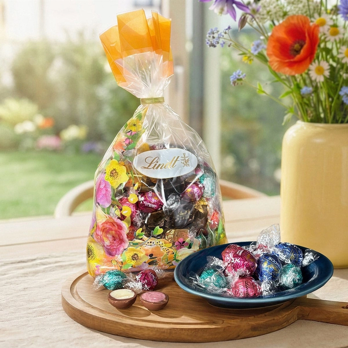 Lindt Schokoladen-Ostergeschenk mit Blumen und frischen Blumen im Hintergrund.