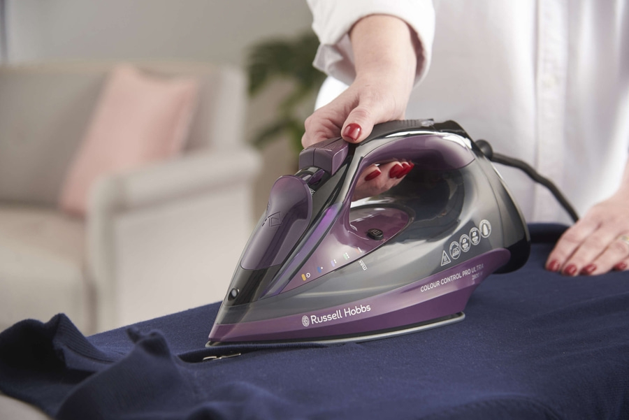 Bügeln mit einem Bügeleisen. Person bügelt ein blaues Kleidungsstück. Russell Hobbs Bügeleisen.