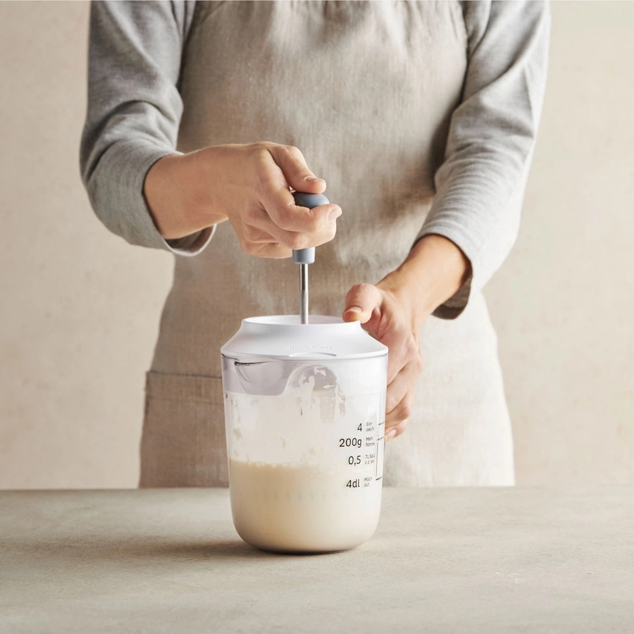 Person rührt in einem Behälter mit einem Mixer. Küche, Kochen, Zutaten.