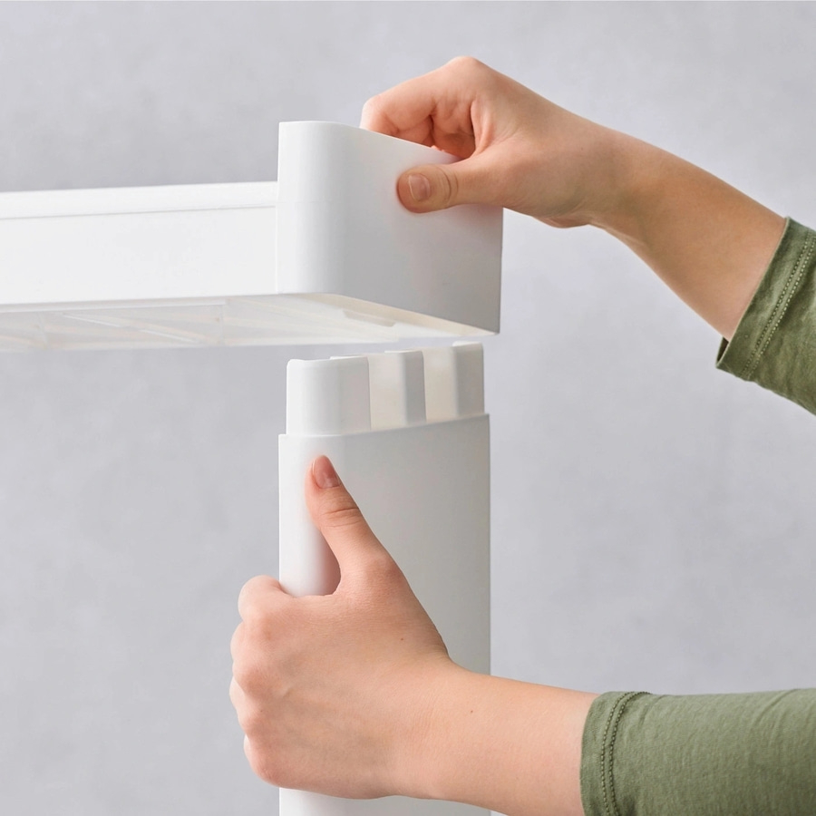 Hände montieren weißes Regal, Nahaufnahme, grauer Hintergrund, grüne Kleidung