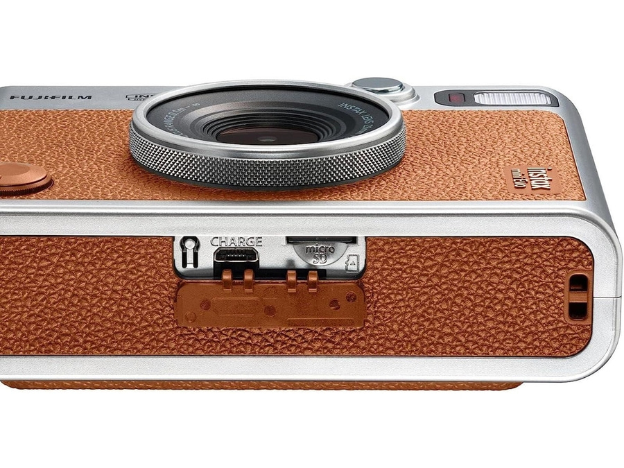 Nahaufnahme einer braunen Fujifilm Instax Mini Evo Kamera mit USB-Ladeanschluss und Micro-SD-Kartenslot