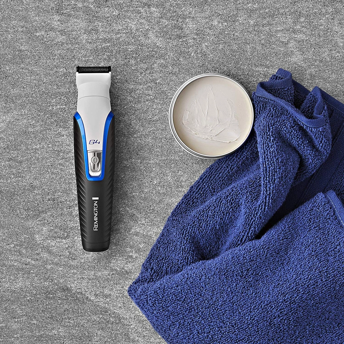 Rasierer, Creme, Handtuch auf grauem Hintergrund. Pflegeprodukte.