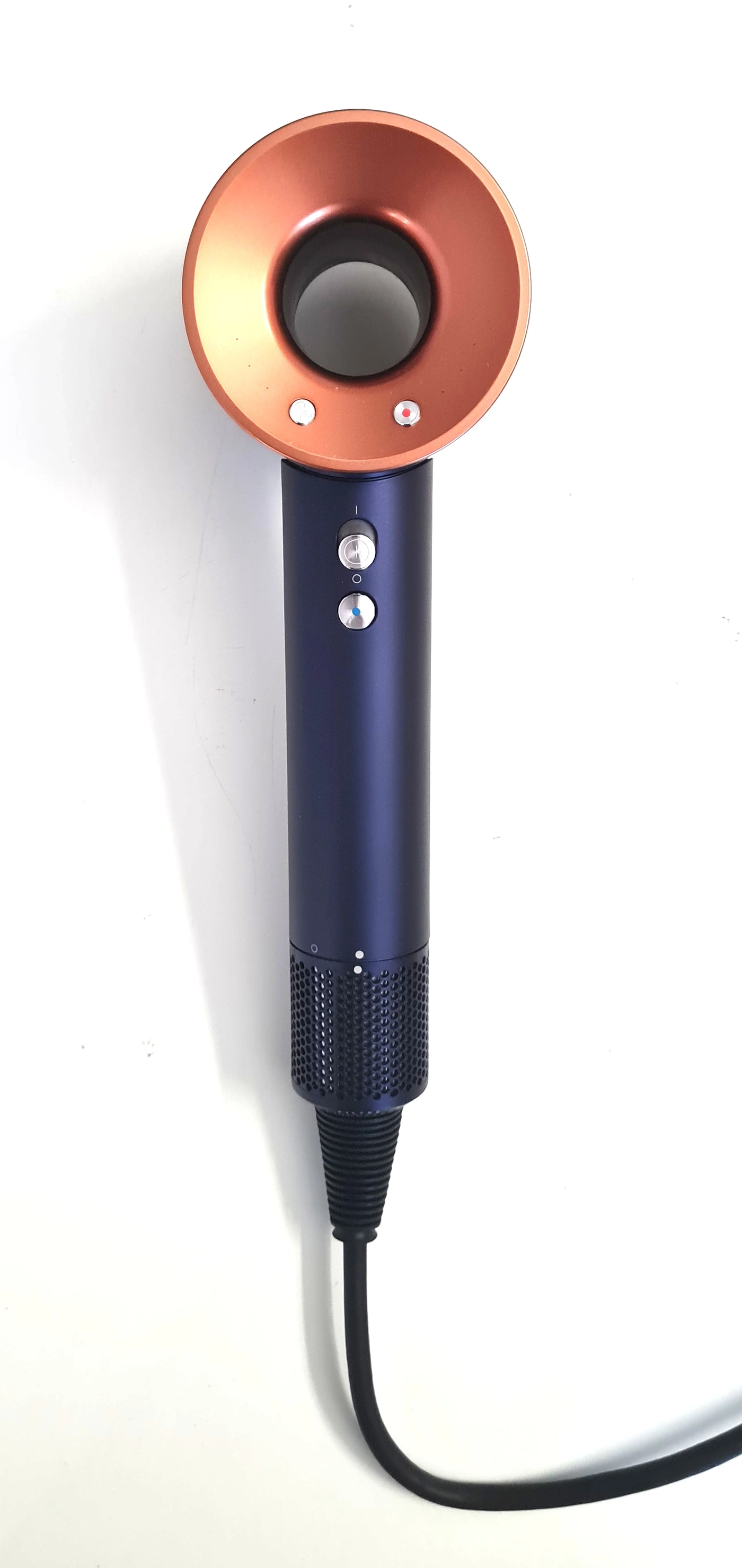 Ein blauer Dyson Haartrockner mit kupferfarbenem Ring und schwarzem Kabel auf weißem Hintergrund.