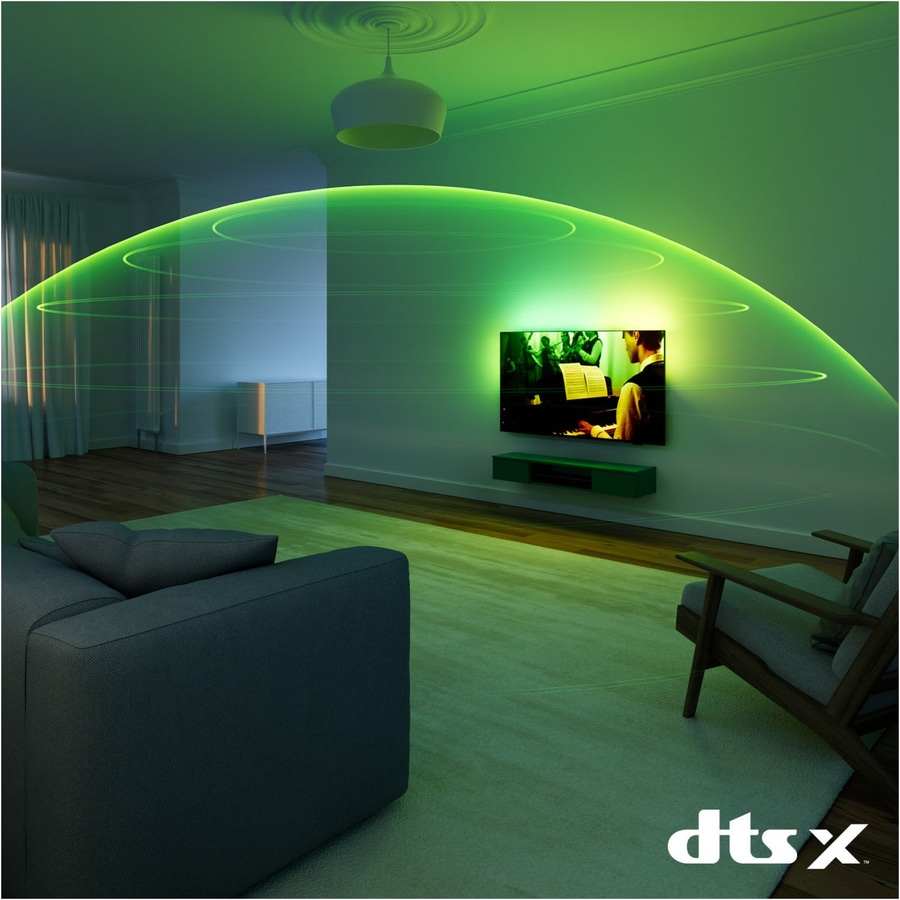 Wohnzimmer mit TV, grünen Lichteffekten und DTS:X-Logo. Gemütliche Atmosphäre.