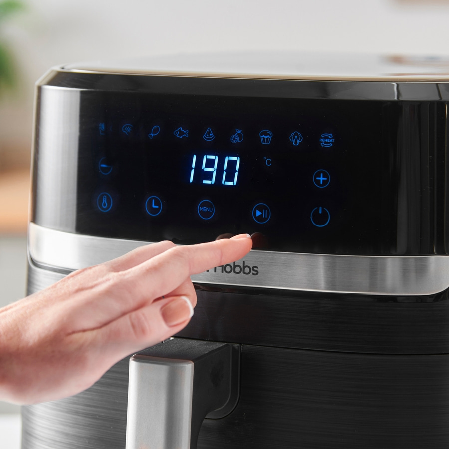 Nahaufnahme eines Airfryers mit einer Hand, die eine Taste drückt, Temperatur 190°C