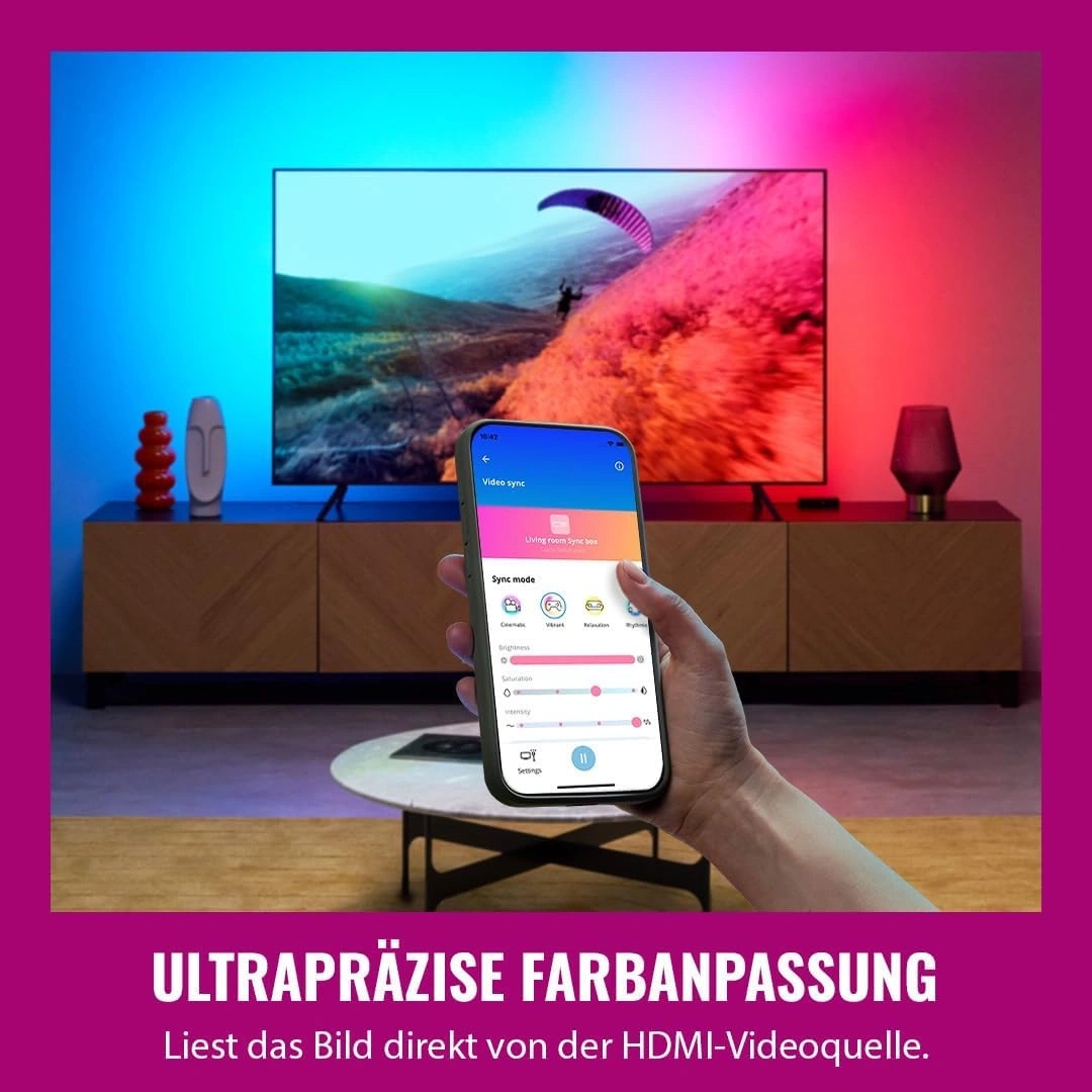 Eine Hand hält ein Smartphone, das die Farbsteuerung für ein Fernsehgerät anzeigt, das mit LED-Licht synchronisiert ist.