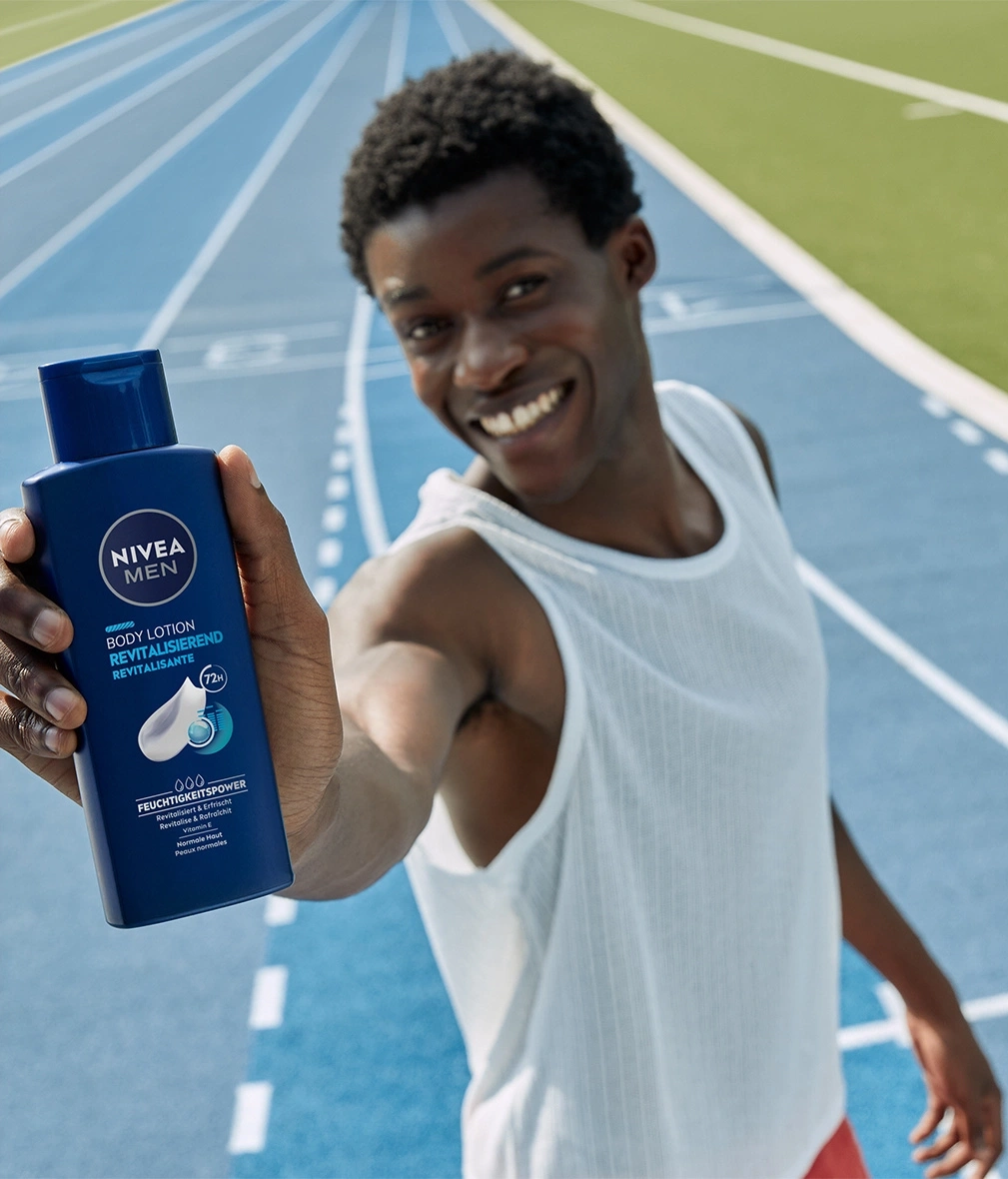 Mann hält Nivea Men Body Lotion, lächelt auf einer blauen Laufbahn