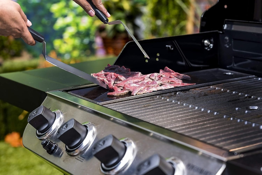 Grillen von Fleisch auf einem Grill mit Spateln, Nahaufnahme