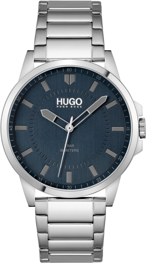 Helles Armbanduhr-Zifferblatt mit HUGO-Logo und silbernen Zeigern und Indizes.
