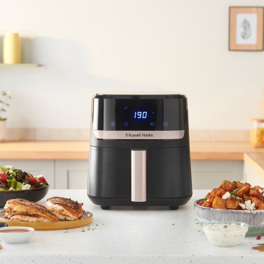 Schwarze Heißluftfritteuse mit Essen auf einem Tisch, Russell Hobbs