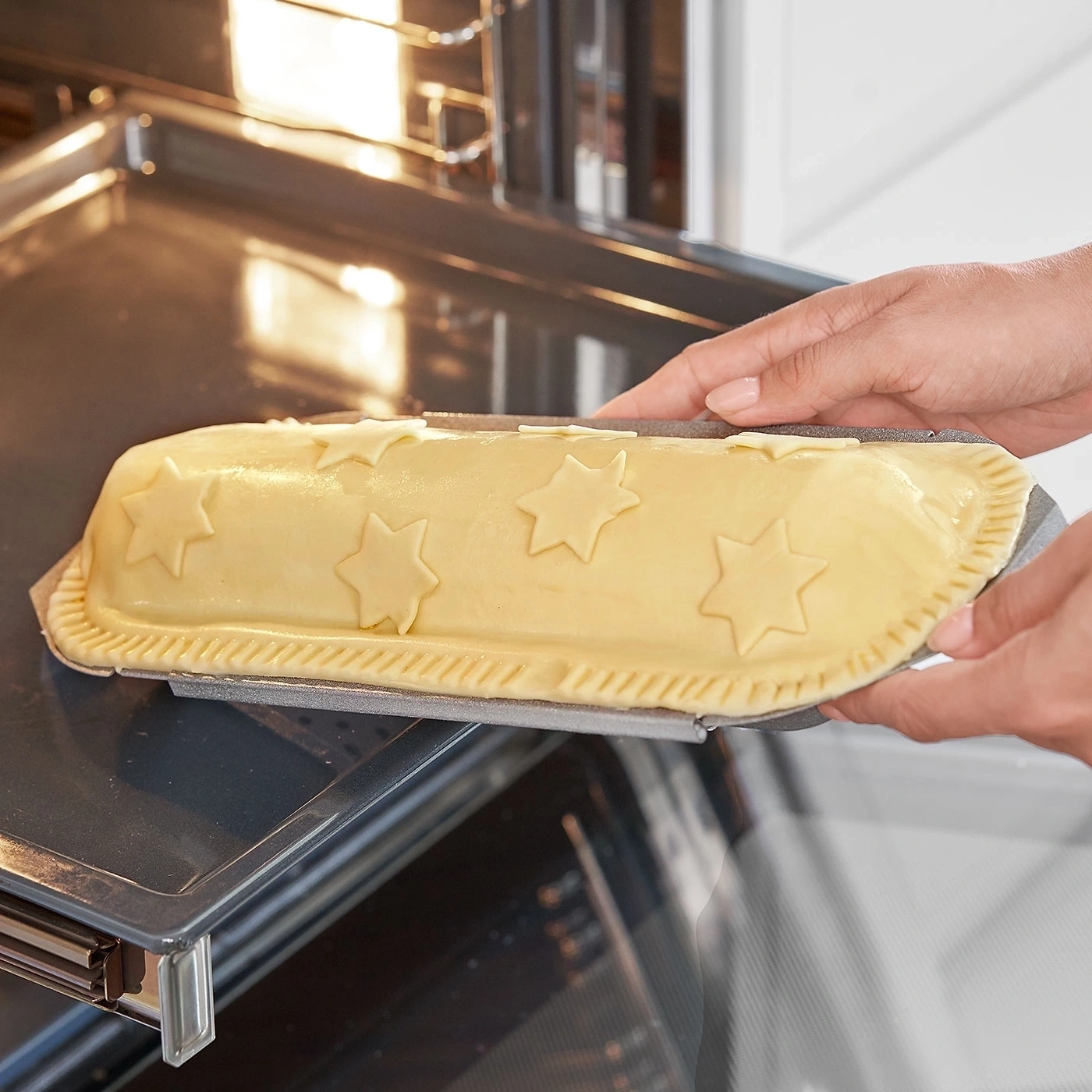 Person legt Kuchen mit Sternen in den Ofen zum Backen.