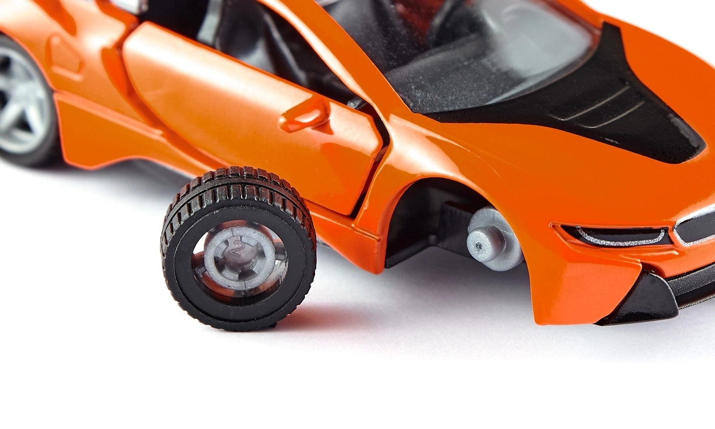 Oranges Spielzeugauto mit abgenommenem Rad auf weißem Hintergrund