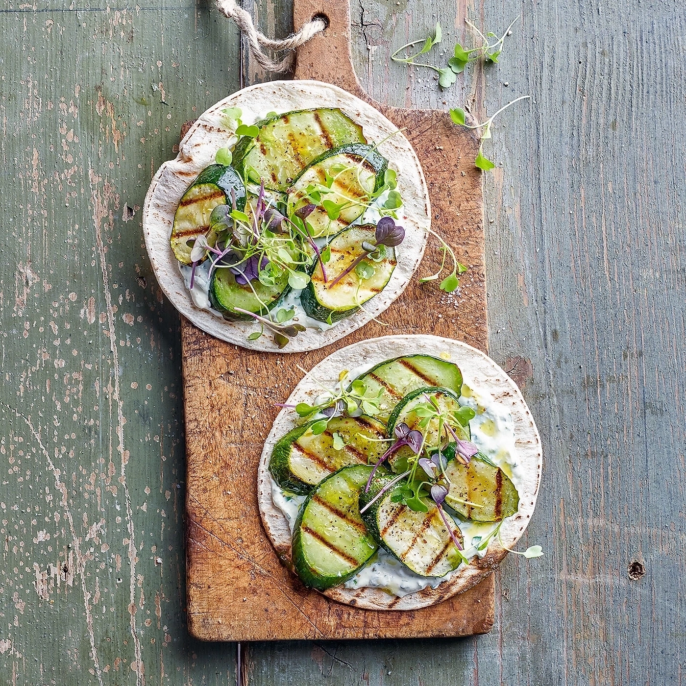 Gegrillte Zucchini-Tacos auf Holzbrett mit Kräutern und Soße