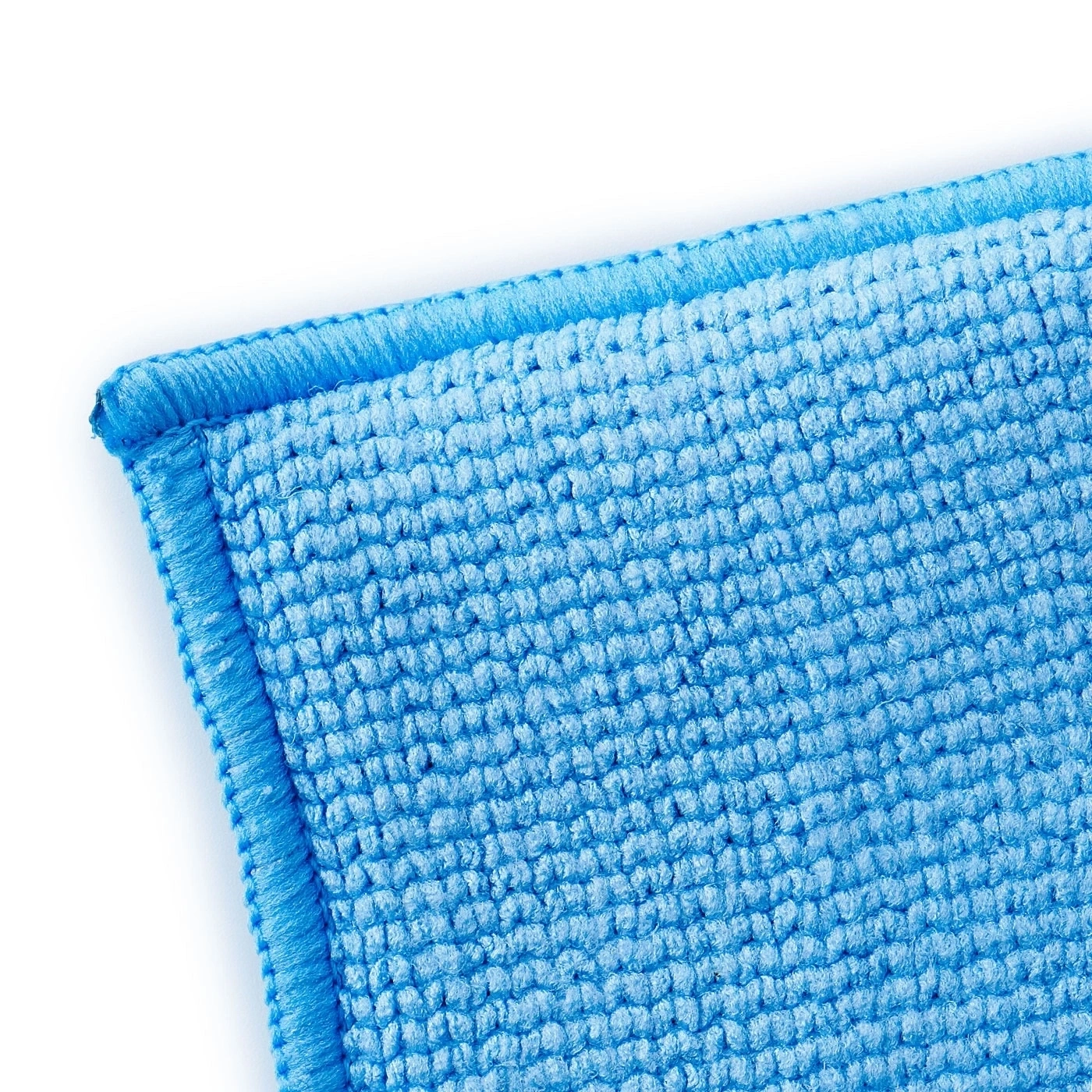 Nahaufnahme eines blauen Mikrofasertuchs mit Textur und Saum, isoliert auf Weiß
