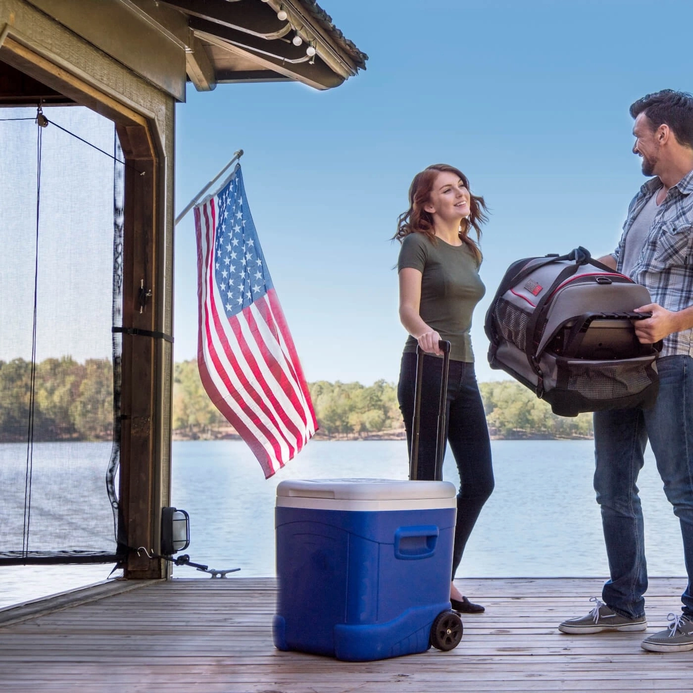 Paar am See mit Kühler, Tasche und amerikanischer Flagge. Urlaub.