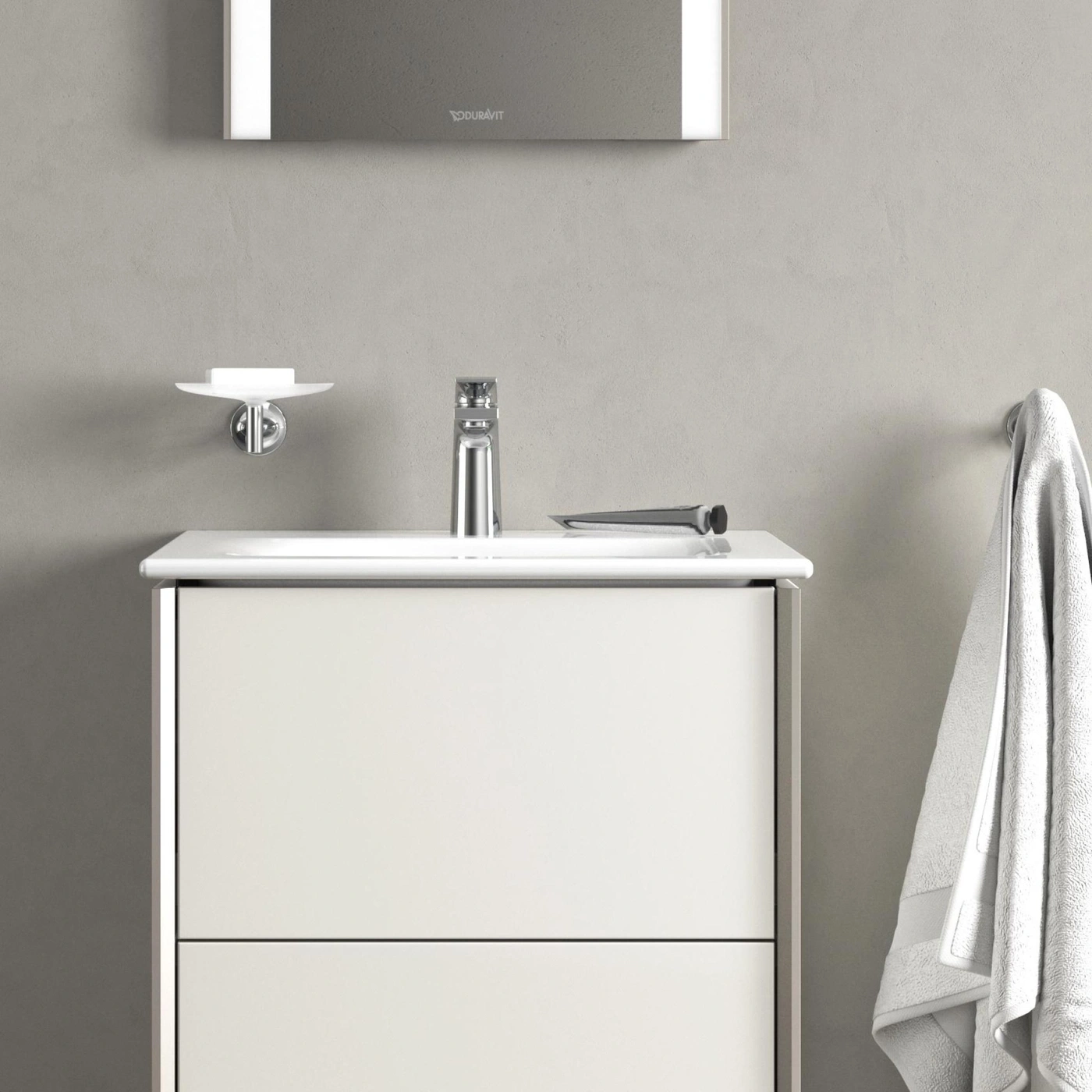 Badezimmer mit Waschbecken, Spiegel, Seifenschale und Handtuch