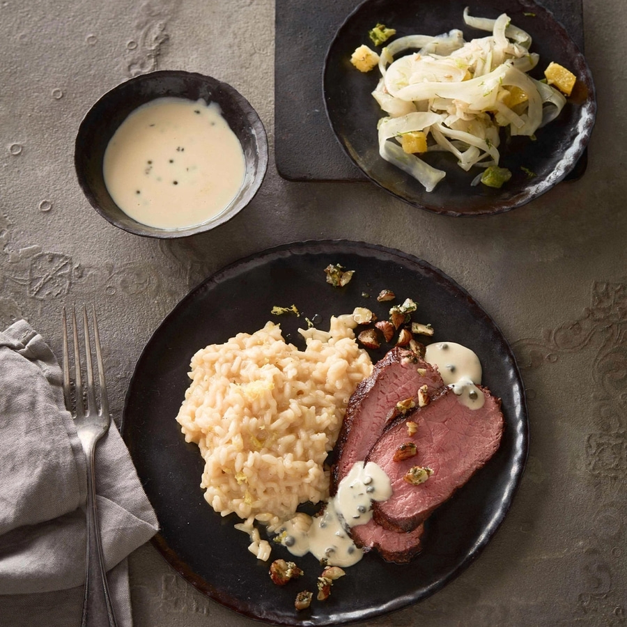 Teller mit Fleisch, Risotto, Sauce und Salat, serviert