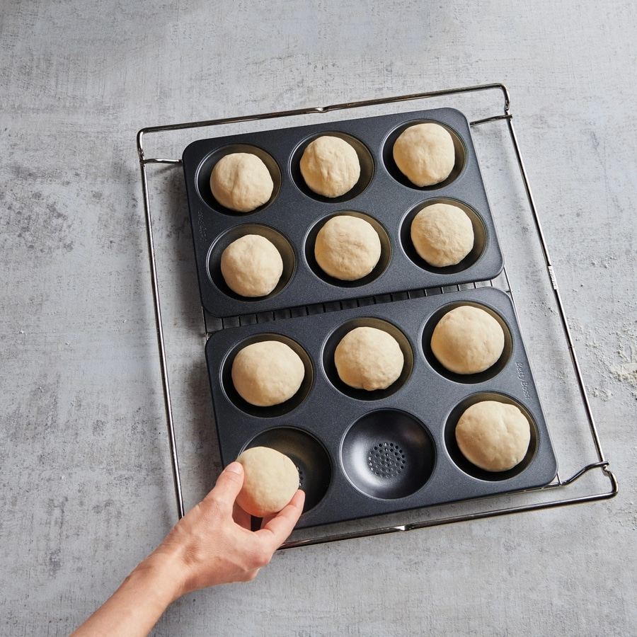 Hände legen Teigkugeln in eine Backform. Backen von Brötchen. Backen von Brot.