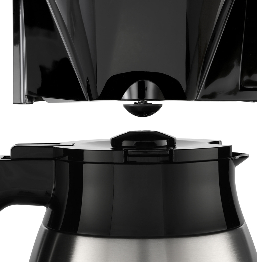 Nahaufnahme eines schwarzen Kaffeemaschinenteils mit Edelstahlbasis und Deckel