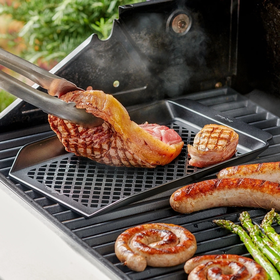 Grill mit Fleisch, Würstchen und Spargel. Essen wird mit Zange gegrillt.