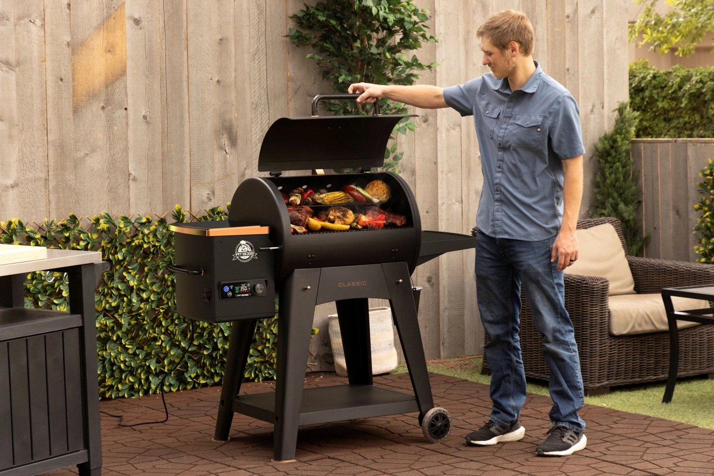 Mann öffnet Grill mit Essen und Gemüse im Garten