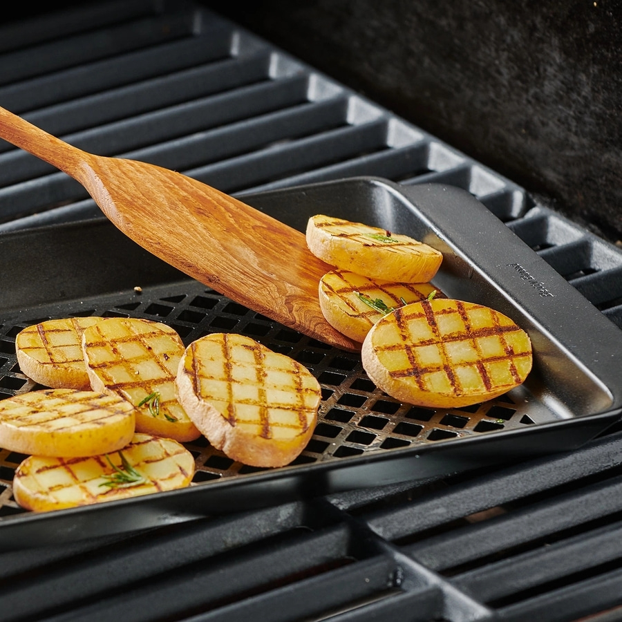 Gegrillte Kartoffelscheiben auf einem Grillrost mit einem Holzspatel
