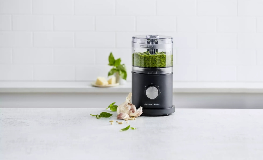 Küchenmaschine mit Pesto, Knoblauch und Zutaten auf weißem Tisch