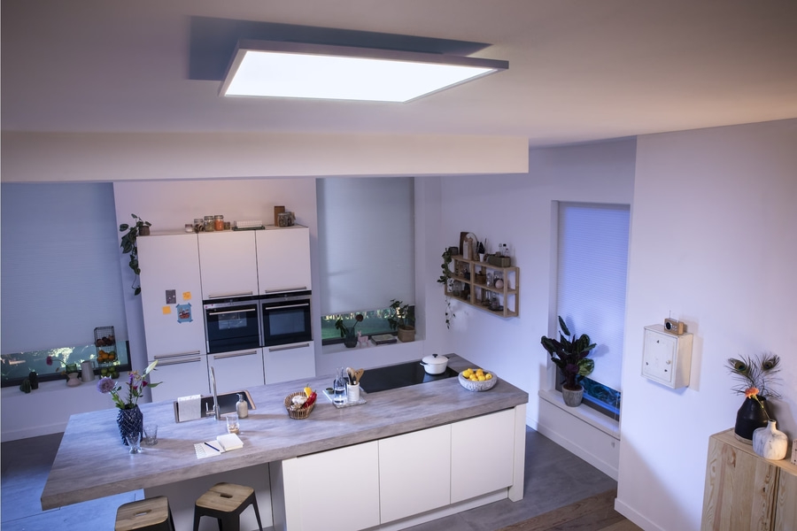 Moderne Küche mit Insel, Deckenleuchte, Pflanzen und Dekoration. Helles, minimalistisches Design.
