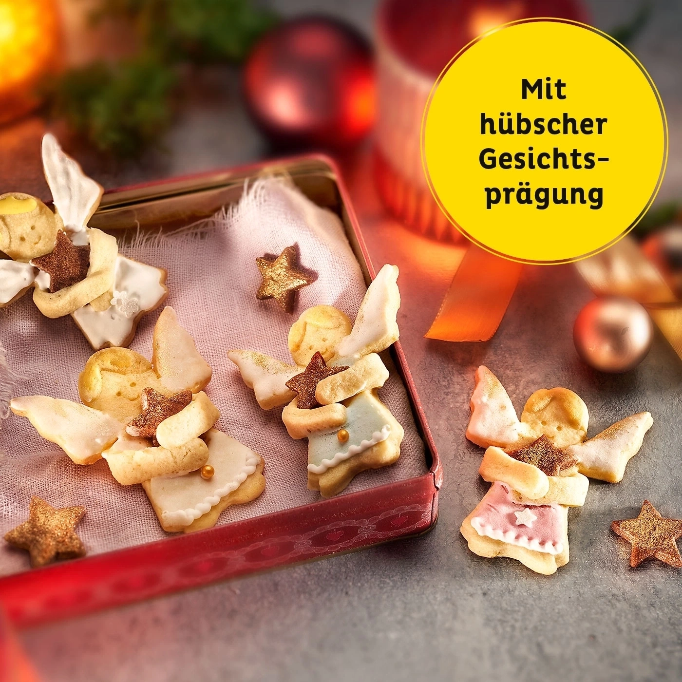 Engel-Kekse in einer roten Dose mit Sternen und Text auf gelbem Hintergrund.