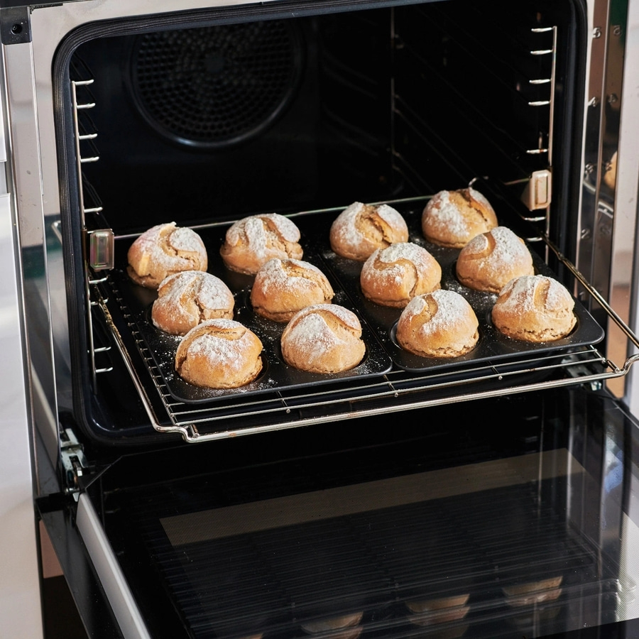 Ofen mit Brötchen, die mit Puderzucker bestäubt sind, gebacken.